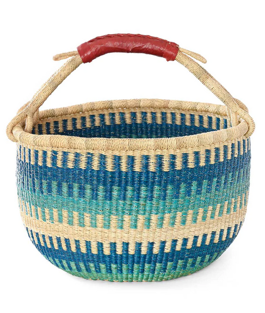 Light and dark blue patterned woven basket with a brown leather handle on a white background