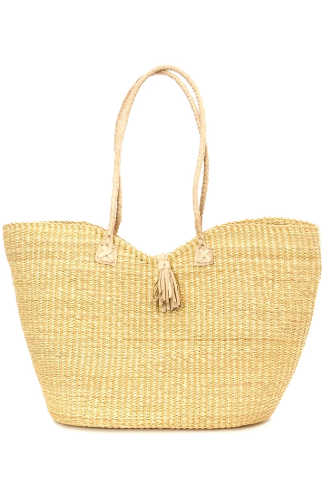 A beige tote bag made from elephant grass with leather handles and a tassel closure.